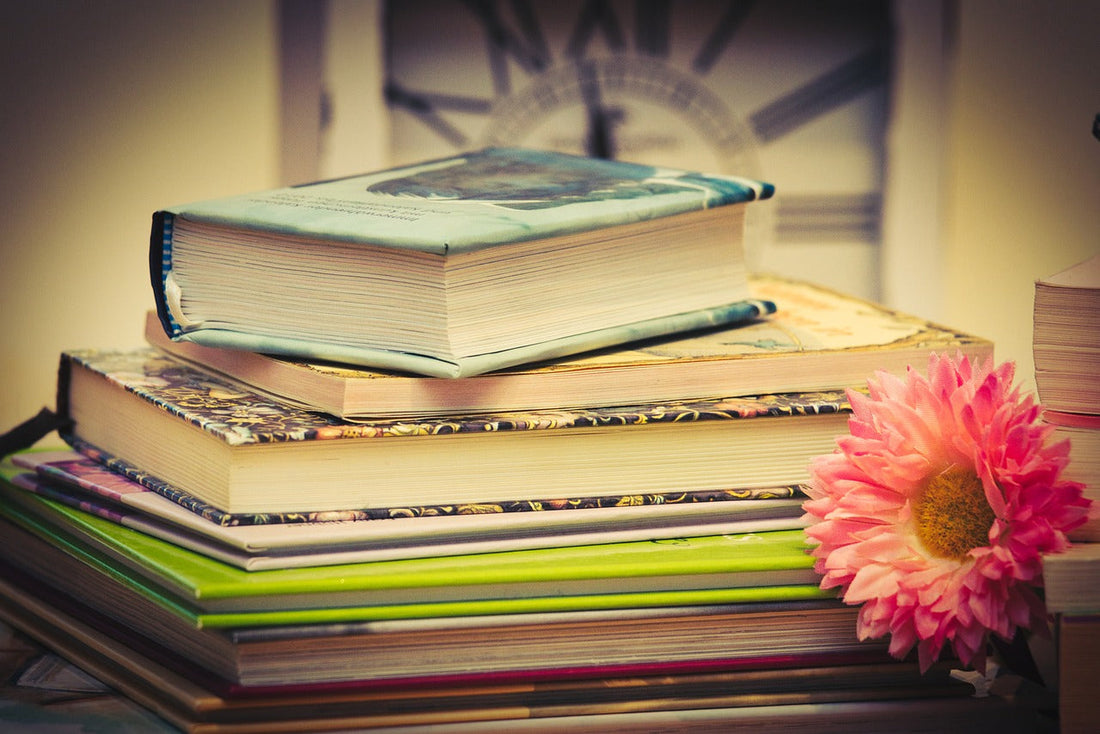 stack of books with a carnation to the right