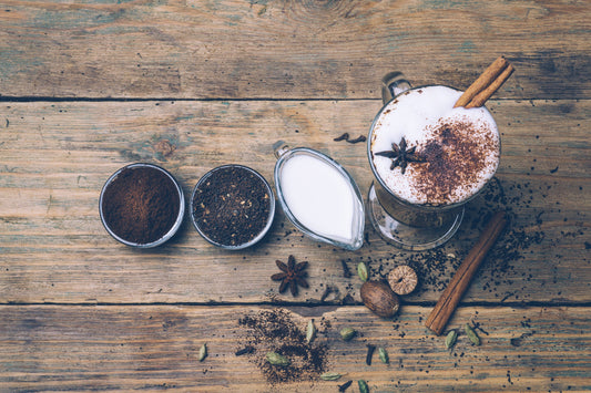 the ingredients for a chai latte setting on a wooden table with a ready latte