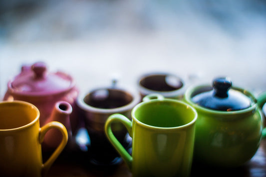 A display of different solid colored teapots and cups